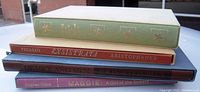 Stack of four books showing cloth-bound spines in green, red, blue and burgundy