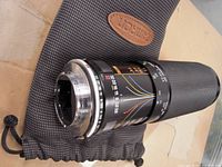 Side view of Tamron macro lens showing distance and aperture scales, mounted on custom Nikon drawstring pouch.