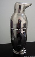 Front view of the penguin figural cocktail shaker showing the smooth silvered surface and beak prominently.