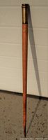 Full view of the wooden swag stick with brass cap, showing length and condition against a neutral background.