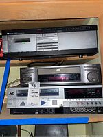 Nakamichi LX-3 cassette deck and two JVC VHS players stacked on shelf with tape deck label