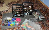 Full view of the costume jewelry lot showing multiple pairs of earrings on black display stands plus plastic bags with loose jewelry.