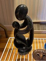 Photo of black polished stone mother and child figurine showing front view with smooth abstract design and glossy finish.