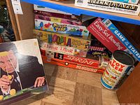 Photo showing stacked vintage board games including Billionaire, Gears!, Scrabble, Mouse Trap, Hoopla, Thing Ding, Sprint, Rebound, Game of the States boxed and more.