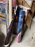 Rolled posters stacked on a concrete floor, some with visible graphics