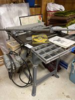 Photo of the Rockwell 10 inch tilting arbor contractor's table saw showing metal frame, large motor, adjustable work table, and some accessories placed on the table.