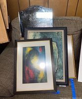 Four items stacked on a chair: beveled edge mirror, Picasso and Boucher framed prints, Le Ba Dang lithograph front.