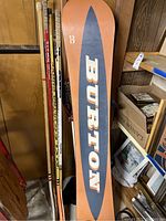 Burton Precision snowboard base view with large Burton logo in orange and blue colors.