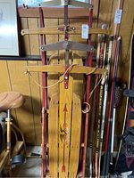 Front view of two stacked vintage Flexible Flyer sleds showing wooden bodies, metal runners, and red arrows with logos, tags visible
