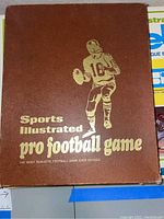 Top view of brown outer box with gold embossed football player and title showing wear and corner damage.