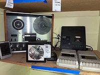 Overview photo shows TEAC A-2300S reel-to-reel tape player with large reel. Next to it is a black Panasonic cassette player, a silver Xenon strobe signal model 1005, Bell & Howell cassette player, and two white Texas Instruments cassette players.