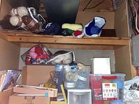 Wide view showing shelves and bins with multiple skeins of different colored yarn, pattern books, knitting needles, and assorted crafting supplies.