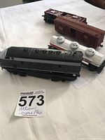 HO scale train engine with Baltimore and Ohio paint scheme, white tanker car, and two brown boxcars on white cloth background