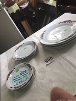 Stack of 4 luncheon plates and 4 dinner plates with holiday poinsettia ribbon design along edges.