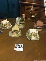Five small collectible cottages by David Winter and Bermuda arranged on wooden table