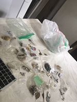 Various pierced earrings scattered on a table with plastic bags, some loose and some grouped.