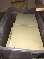 Two Kodak slide carousels stacked inside a transparent plastic storage bin, showing their rectangular shape and off-white plastic material.