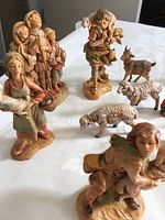 Various nativity figurines including children holding lambs, shepherds, goat, and sheep figurines laid on a table