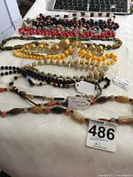 Photo of various chunky necklaces laid out on a white surface including stones with garnets, yellow beads, mixed stone and bead styles.