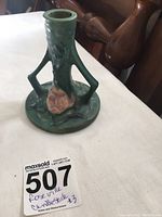 Photo of green Roseville candlestick with Lilly pattern mold 1157-4 1/2 from an angled top view showing textured lily flower detail and wide base.