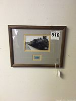 Framed black and white train photograph with postage stamp mounted below, displayed against a wall.