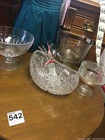 View of all items on table including large cut-glass bowl, clear boat bowl, small pedestal bowls, and metal salad utensils