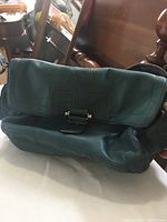 Front view of Tignanello teal leather purse showing flap with buckle detail