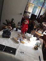 Photo showing various winter-themed figurines and decorations on a table including stuffed and ceramic items, dolls, and other small holiday ornaments.