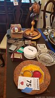 Top view of the entire lot showing a variety of vintage ashtrays, lighters, wooden stand with bird carving, smoking pipe, flask, and coasters on a table.