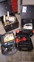 Black & Decker Wizard jigsaw, Mastercraft saber saw, Black & Decker drill and carrying cases gathered on floor