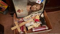 Box of assorted religious articles including framed Jesus wall art, crucifix rosary, candles, and figurines.