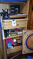Atari console, game cartridges, joystick and paddle controllers, diecast vehicles along with other vintage toys such as ball and frisbees on shelves