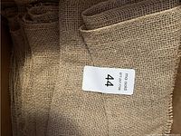Five folded burlap table runners stacked together with a white sticker labeled '44' on top.