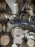 Bags of mixed-size silver metal canning jar lids and round rubber seals for Mason and Bernardin jars.