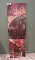 Front view of an abstract art canvas wall hanging with circular shapes in red, brown, and beige tones.