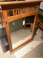 Front view of a large rectangular mirror with wood frame and vertical slats across the top section.