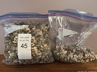 Two partially filled Ziploc bags containing natural stones with a sticker showing lot number.