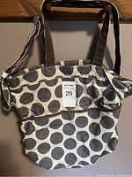 Front and side view of the Thirty-One utility tote bag showing the gray and white polka dot pattern with brown handles and silver hardware on adjustable shoulder strap.