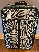 Front view of zebra print suitcase, shows exterior pattern and zipper pockets.