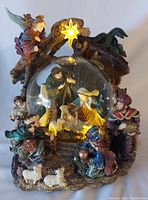Full view of the nativity snow globe showing angel, star, figures, and base