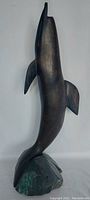 Side view of the dark wood dolphin statue highlighting smooth curves and fins.