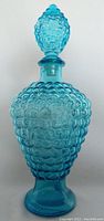 Full view of blue pressed glass decanter with bubble texture and matching stopper