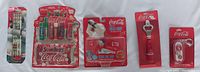 Photo of all four Coca-Cola items in original sealed packages showing overall set condition