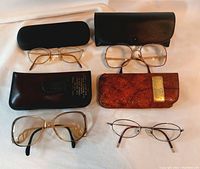 Four pairs of eyeglasses arranged with their respective cases and close-up of eyeglasses and brown leather case