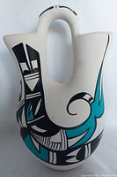 Photo of Navajo wedding vase showing turquoise, black, and white geometric and abstract painted patterns on its double-spouted design.