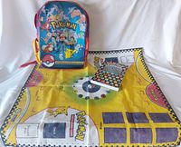Photo of Pokémon backpack, fabric game mat, and handbook laid out together