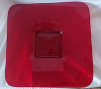Front view of red square glass plate showing the glossy translucent finish and raised central square area
