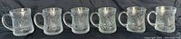 Full view of all six clear glass mugs showing the crocus flower and vertical line pressed glass design, with handles visible.