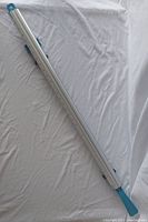 Full length view of the aluminum clamping guide with visible blue plastic end handles and the scale along the side.