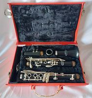 Vito clarinet disassembled inside orange hard case with black plush interior. Shows clarinet body sections, mouthpiece, and keys.